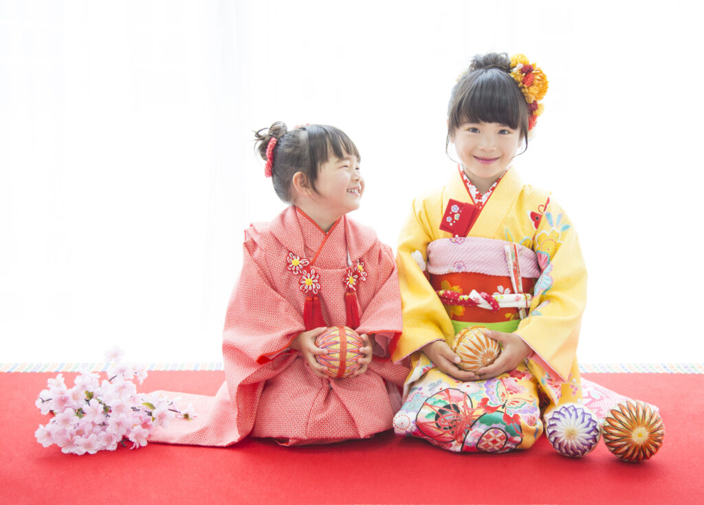 家族衣装：上手に鞠を持ちながら上品に正座のポーズをする姉妹