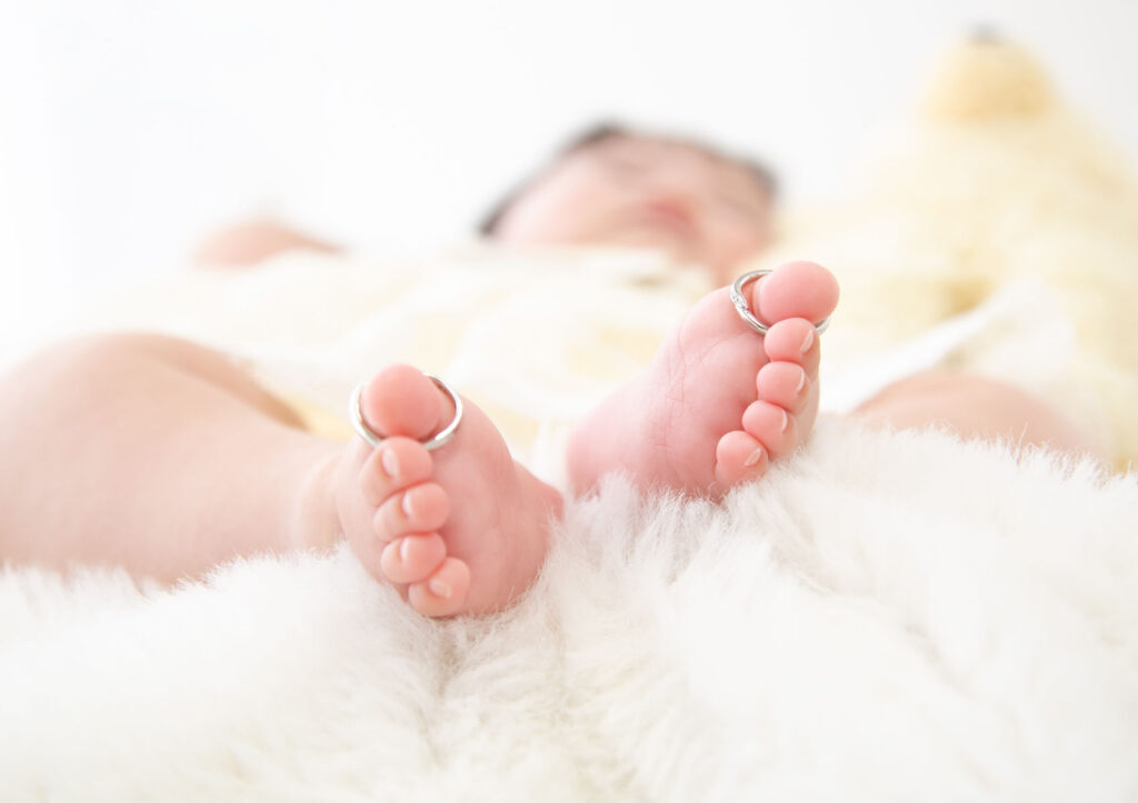 お宮参り：パパとママの結婚指輪を足の指に飾った赤ちゃん