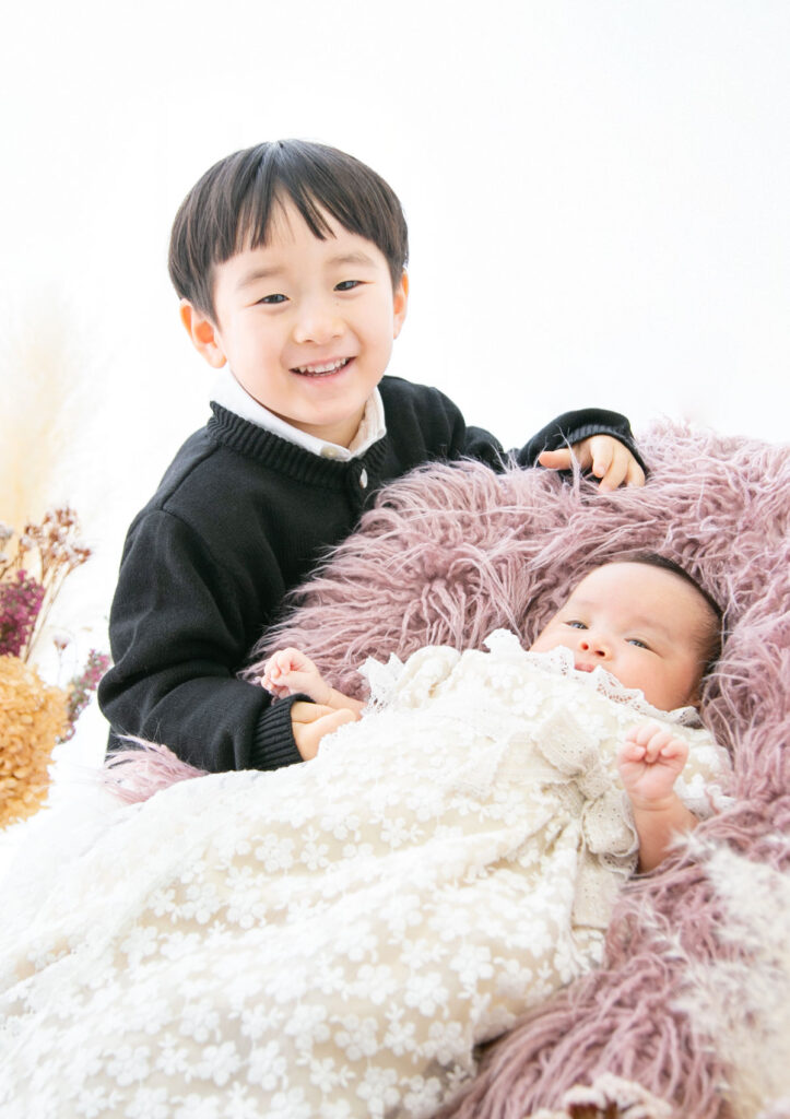 お宮参り：ベビードレスを着てお兄ちゃんと並んだ赤ちゃん