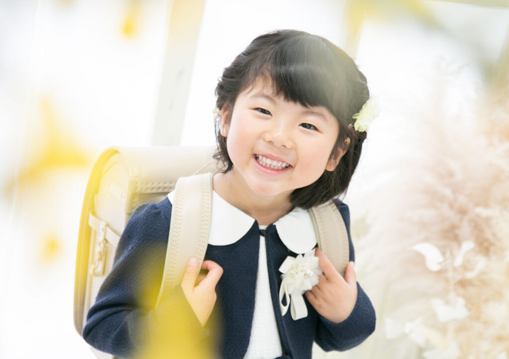入学：キチンとした服装にベージュのランドセルを背負って笑っている女の子