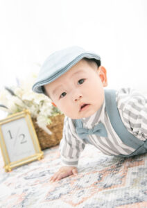 ベビー・バースデー：蝶ネクタイとサスペンダーでおめかししハイハイする男の子