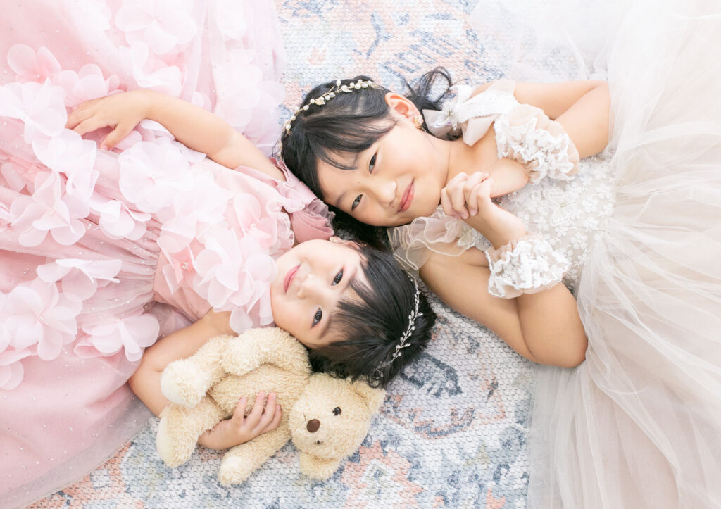 家族衣装：ノストラジックな絨毯の上に二人でごろんと寝転がってキュートなポーズをとる姉妹