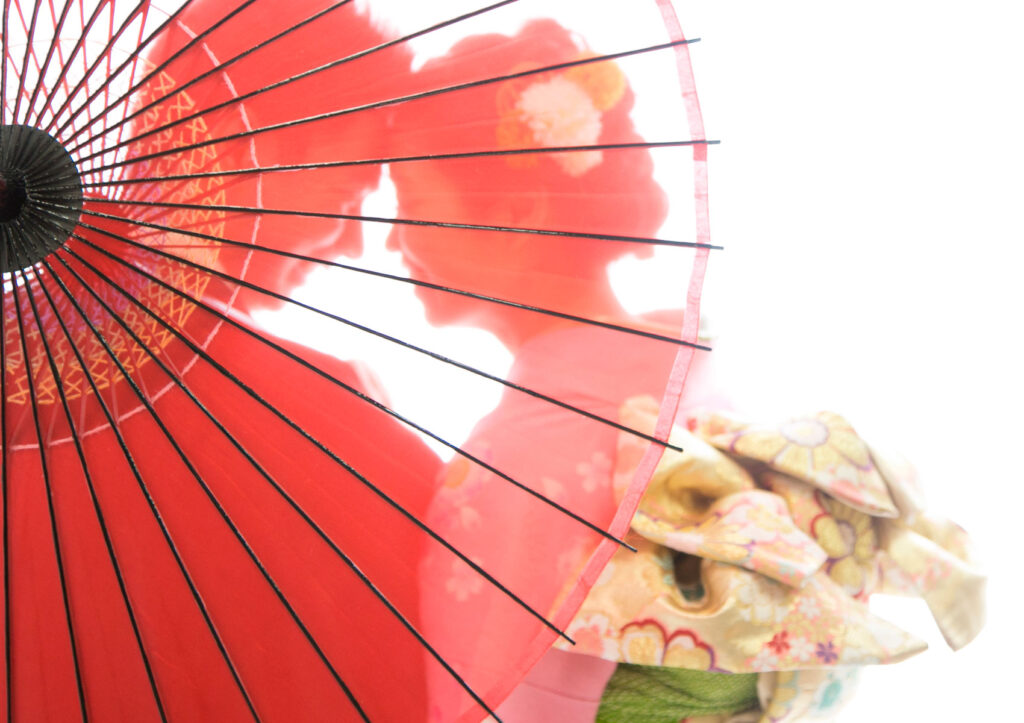 ウェディング：赤い和傘を透かして見つめ合う、和装の新郎新婦