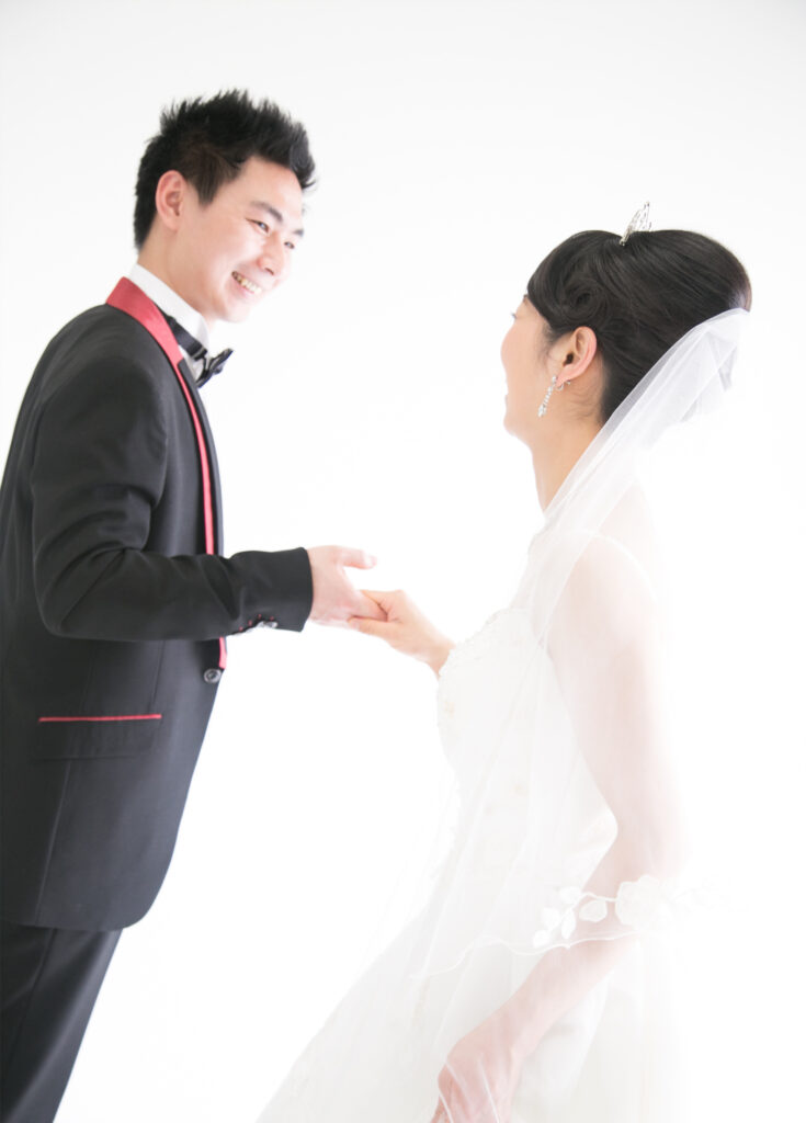 ウェディング：ウェディングドレスを身にまとい、タキシードを着た新郎に手を引かれる新婦