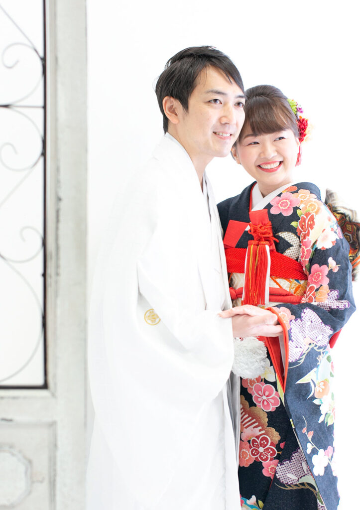 ウェディング：引き振袖を着た新婦の手を優しくとる、白い紋付き袴を着た新郎