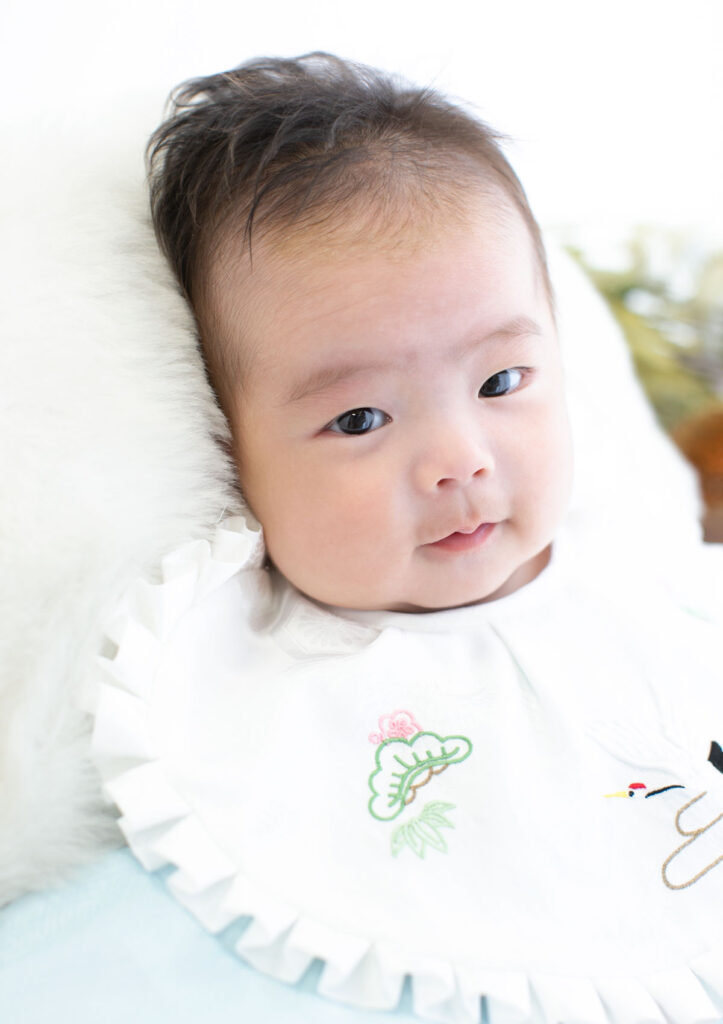 お宮参り：水色の産着を着てカメラを見つめる男の子の赤ちゃん