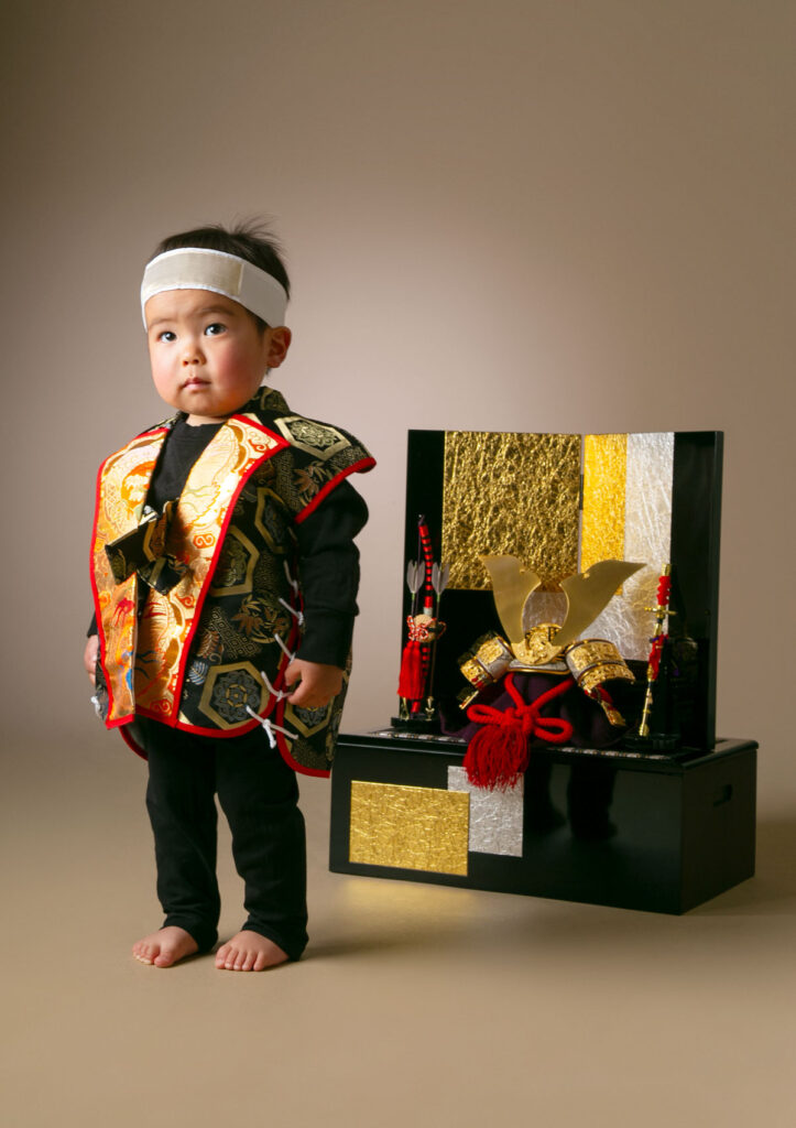 お節句：兜人形と並んで勇ましく立つ男の子