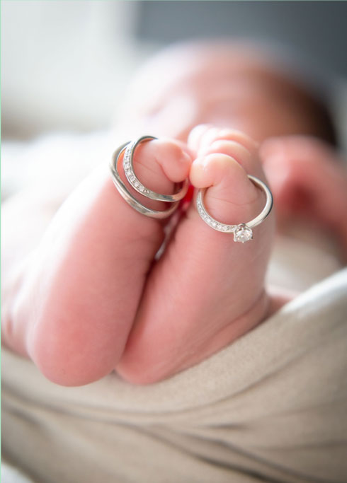 ニューボーン：パパとママの結婚指輪を足の指に飾って眠る赤ちゃん
