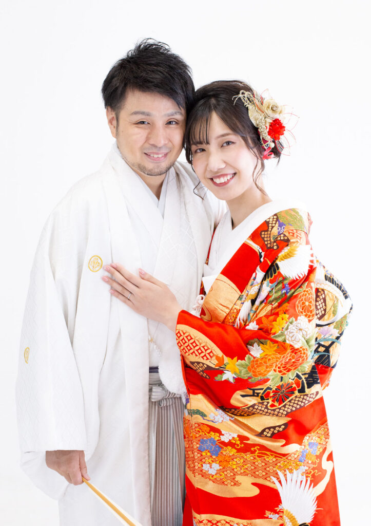 ウェディング：赤く鮮やかな色打掛を着た新婦と白い紋付袴を着た新郎