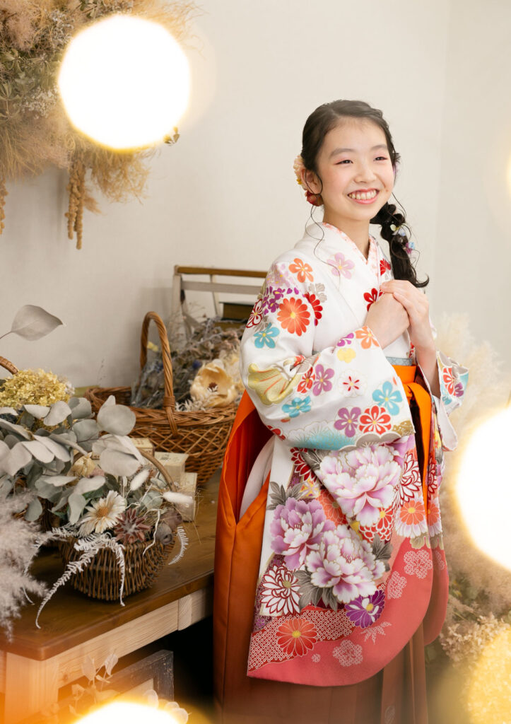 卒業：キラキラ光るライトに囲まれて胸の前で手を重ねて満面の笑みを浮かべる女の子