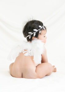 ベビー・バースデー：天使の羽を付けた背中越しに横顔を見せる赤ちゃん