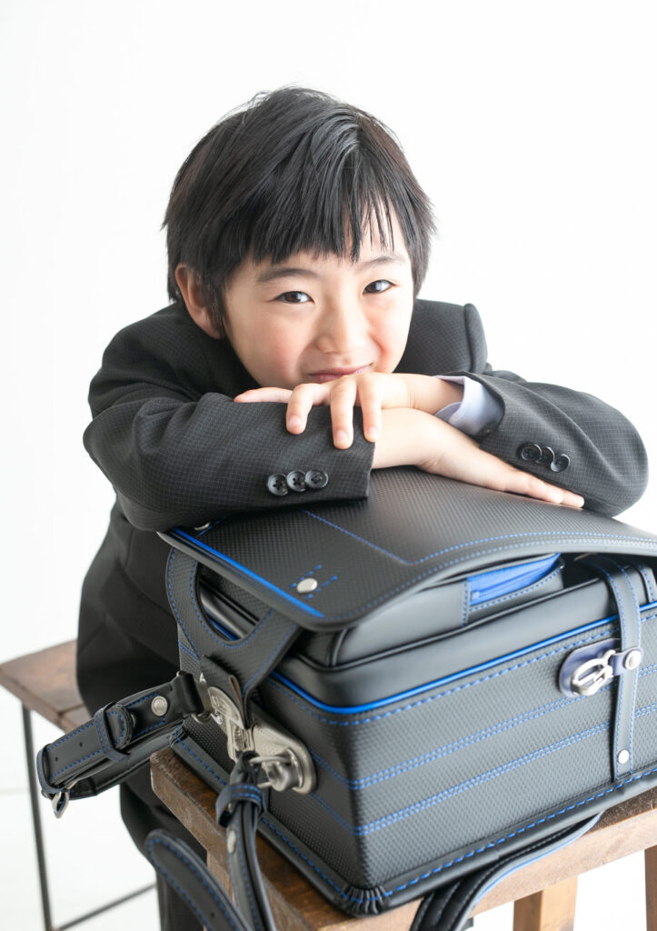 入学：ランドセルにもたれかかって、ニヤリと笑う男の子