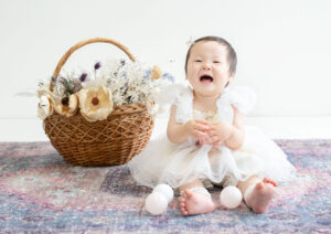 ベビー・バースデー：白いドレスとレースのアクセサリーを着た笑顔の女の子