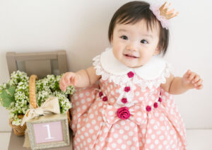ベビー・バースデー：水玉ピンクのドレスを着て微笑む女の子