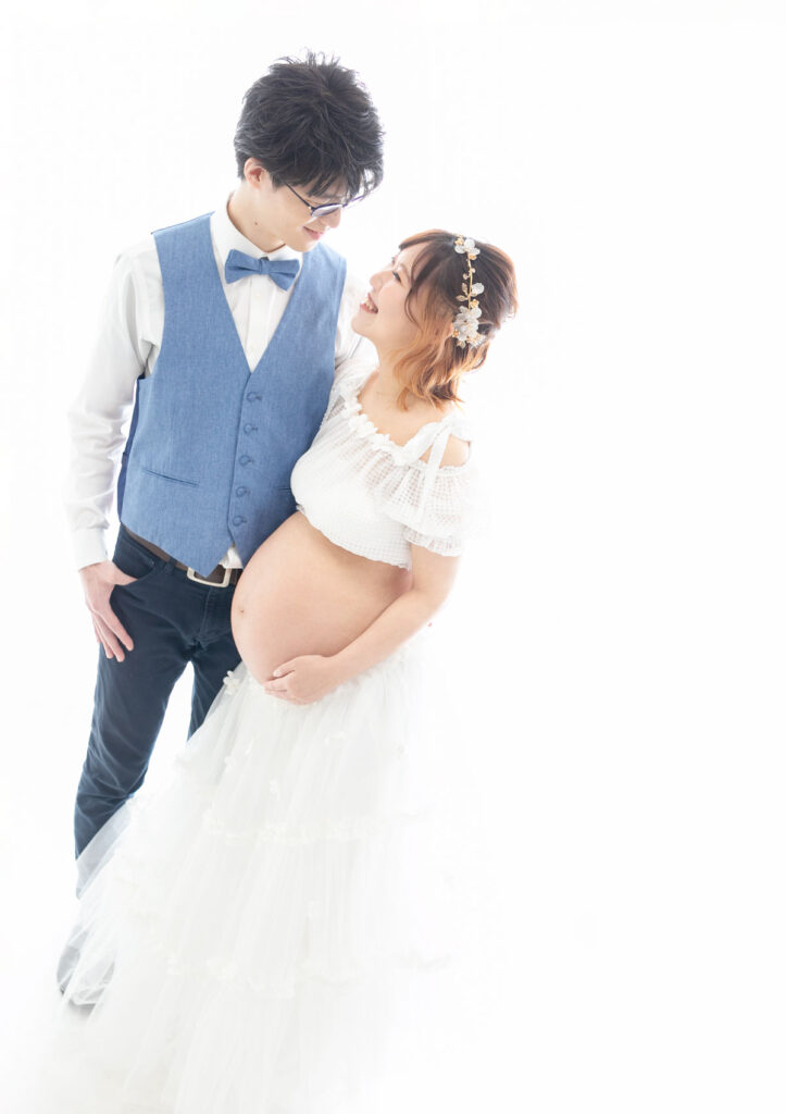 マタニティ：ドレスアップしたパパとママが寄り添い笑顔え見つめ合うツーショット