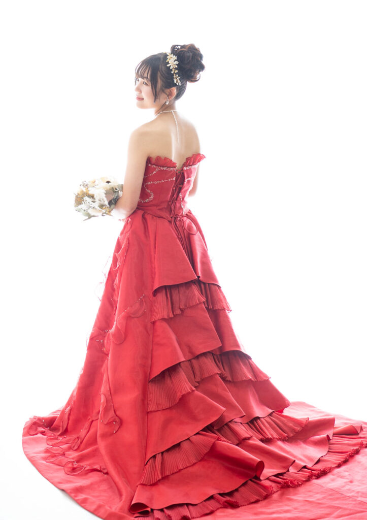 成人式：花束を両手に持って微笑むレッドのカラードレスを着た女性