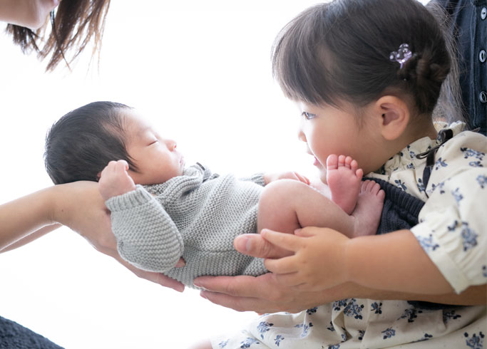 ニューボーン：パパとママ、お姉ちゃんに優しく抱えられて眠る赤ちゃん