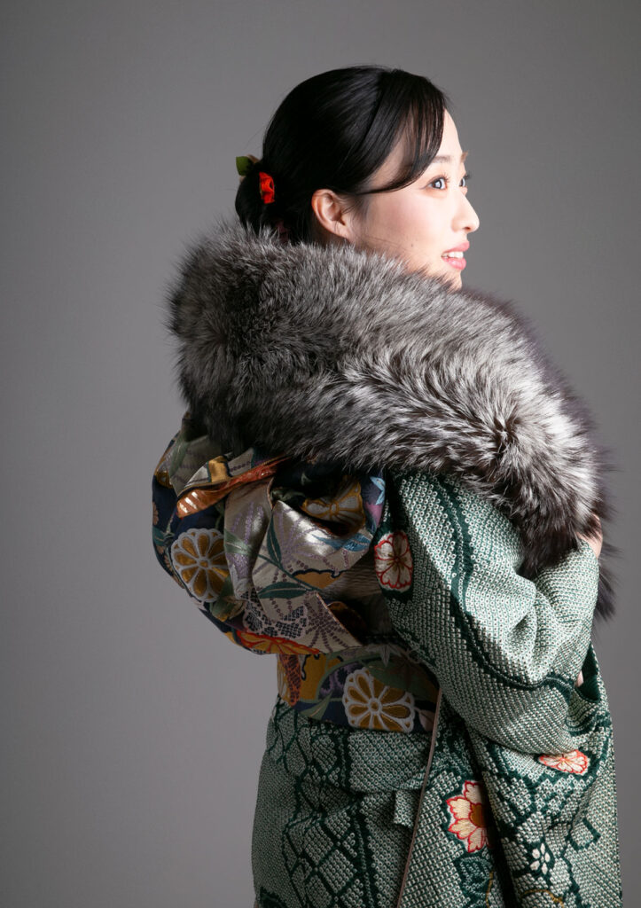 成人式：知性を感じる深緑色の振袖にグレーのファーを着用して微笑む女性