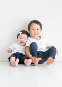 ベビー・バースデー：白シャツにネイビーのボトムを合わせたペアルック風の兄妹