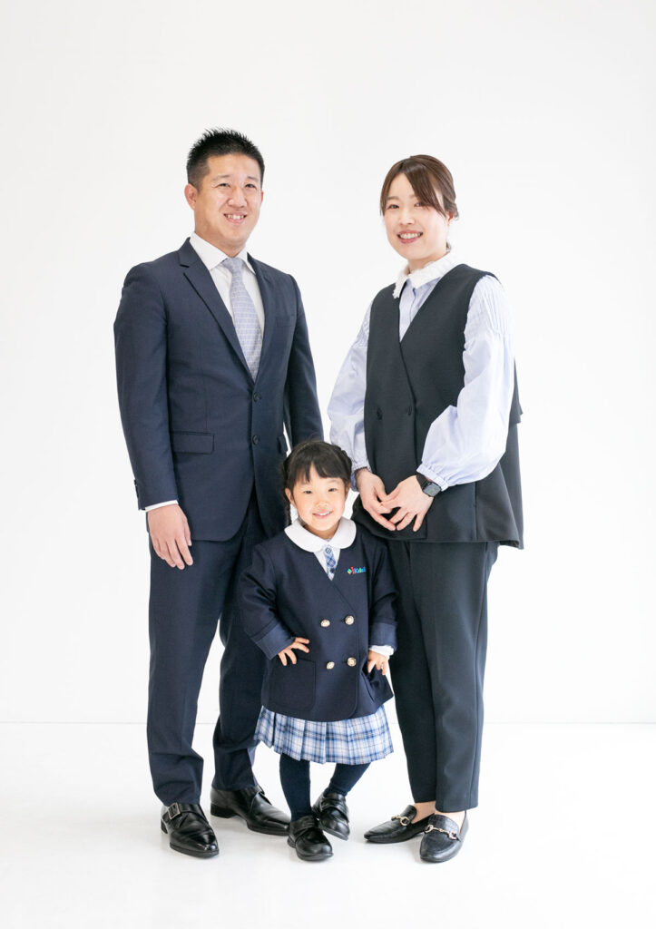 入園：ブルーのチェックがかわいい制服を着た、決めポーズをする女の子と両親