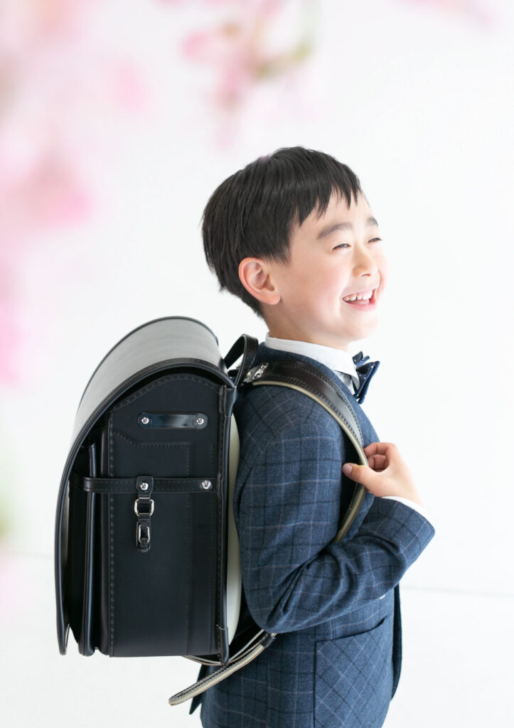 入学：おしゃれなスーツを着て優し気にほほえむ黒いランドセルを背負った男の子