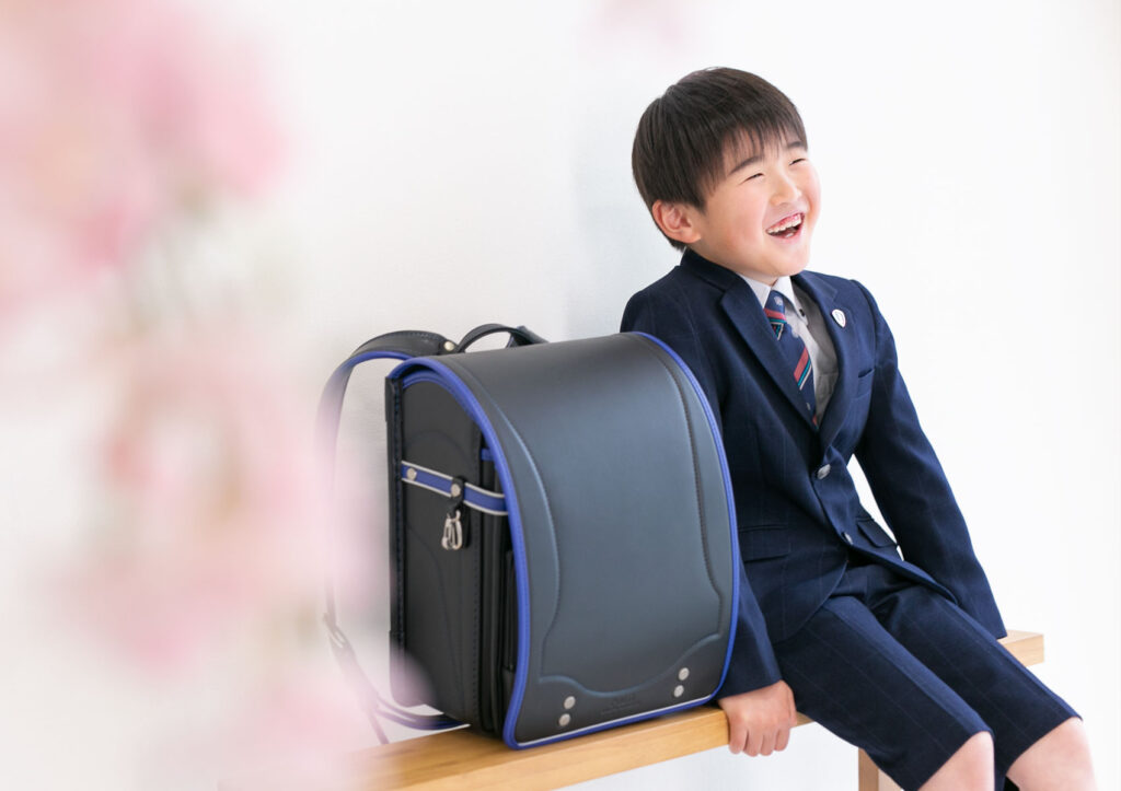 入学：桜とランドセルと共に、朗らかに笑う男の子