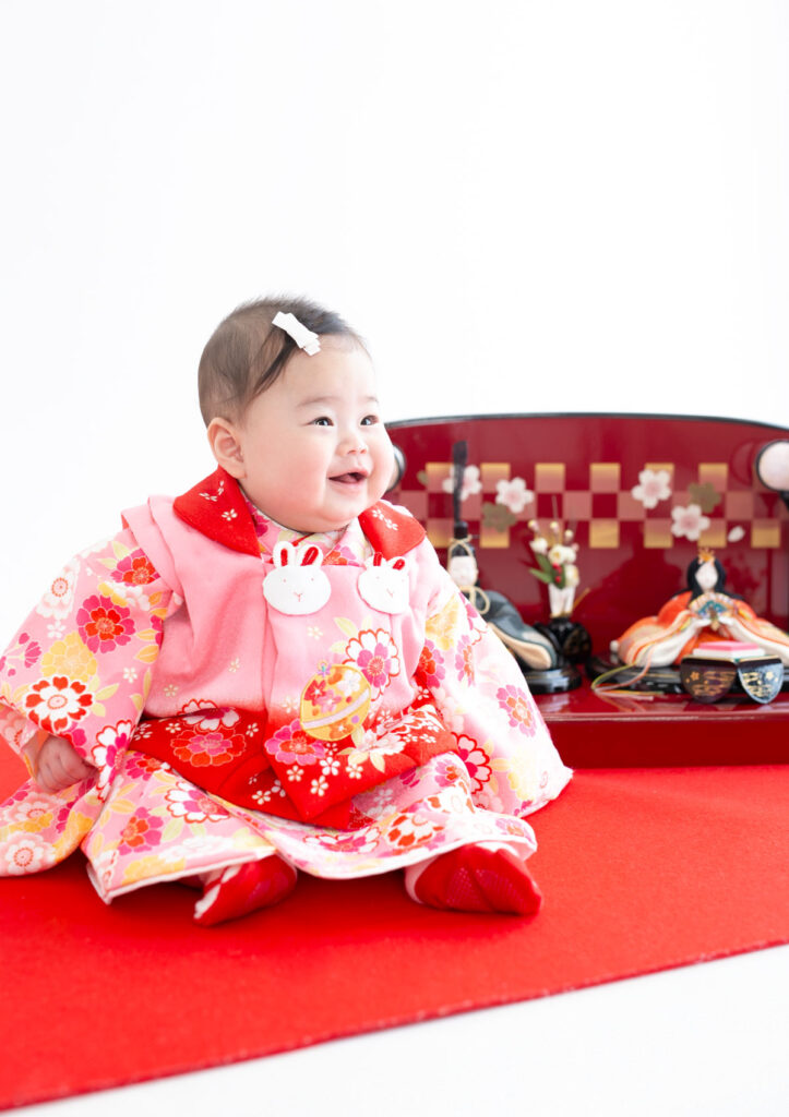 お節句：着物を着てひな人形と並んで微笑む女の子の赤ちゃん
