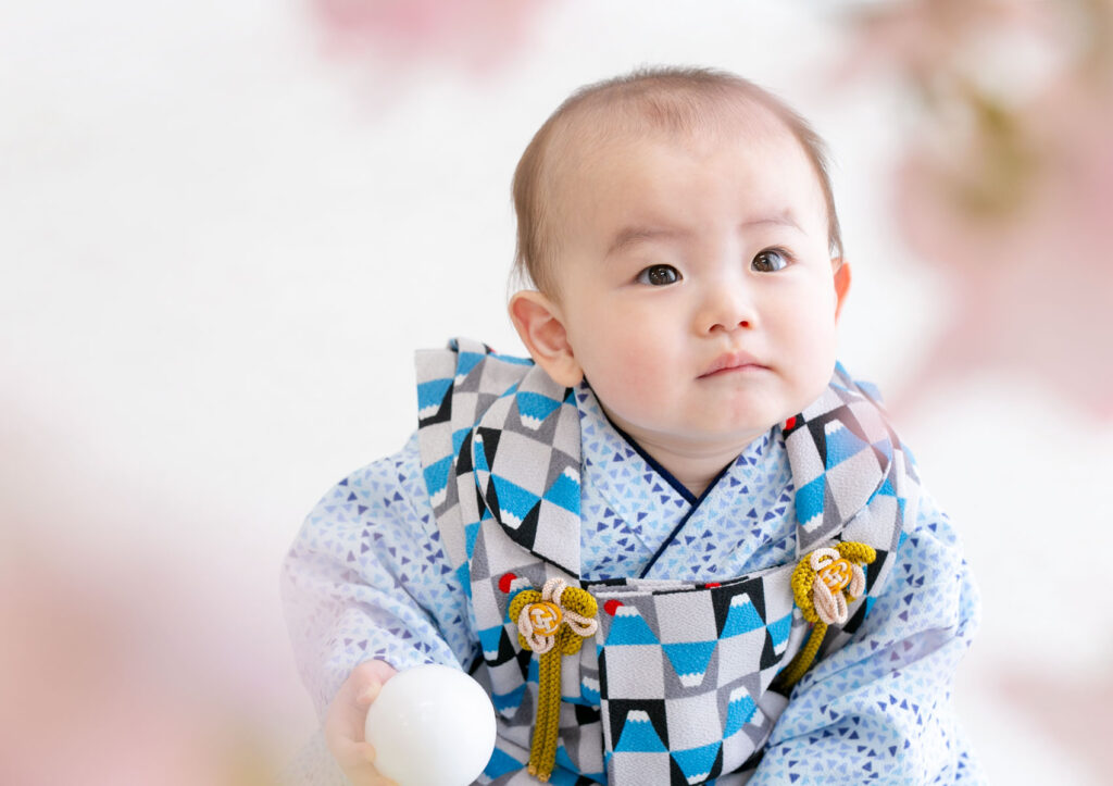 お節句：着物を着て桜越しに空を見つめる男の子の赤ちゃん