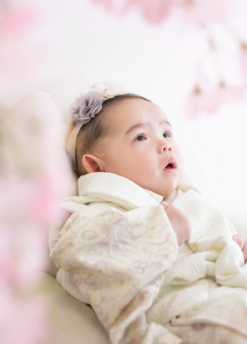 お節句：着物を着て桜越しに空を見つめる女の子の赤ちゃん