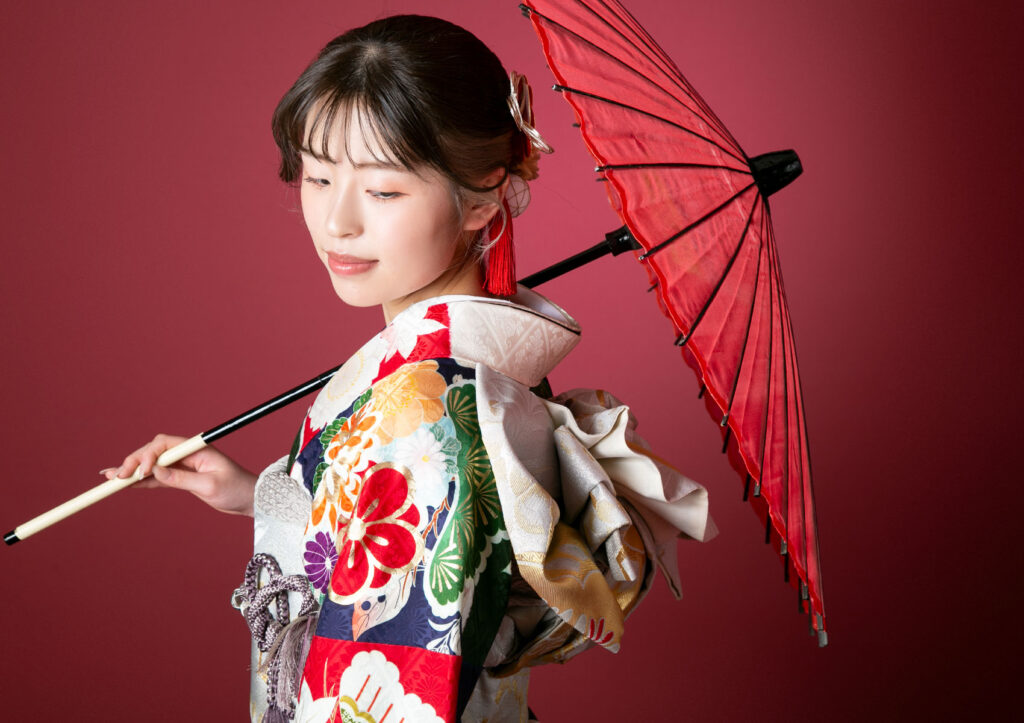 成人式：和傘と雅に持って、流し目で美しいポージングをしている振袖の女性
