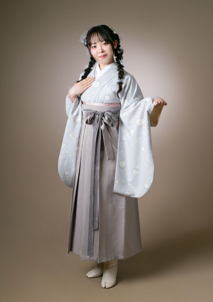 卒業袴：淡色の着物にベルベット素材のリボンを合わせたコーディネートを着用した女性