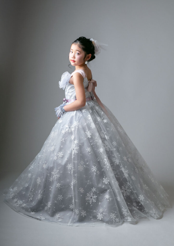 ハーフ成人：グレーベースに雪の結晶がちりばめられた上品なドレスを着た10才の女の子