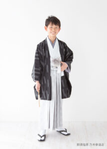 10歳着物：淡いグレーに黒い矢羽柄の着物を着た10才の男の子。