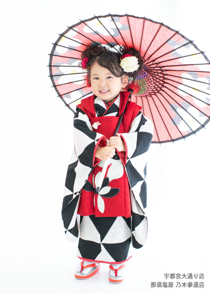 七五三３歳着物：人気ブランド、モダンアンテナの白・黒・赤の斬新なデザインの着物をきた３才の女の子。