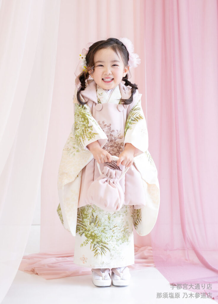 七五三３歳着物：2025年の最新トレンド、ボタニカル柄の着物を着た笑顔の３才の女の子。