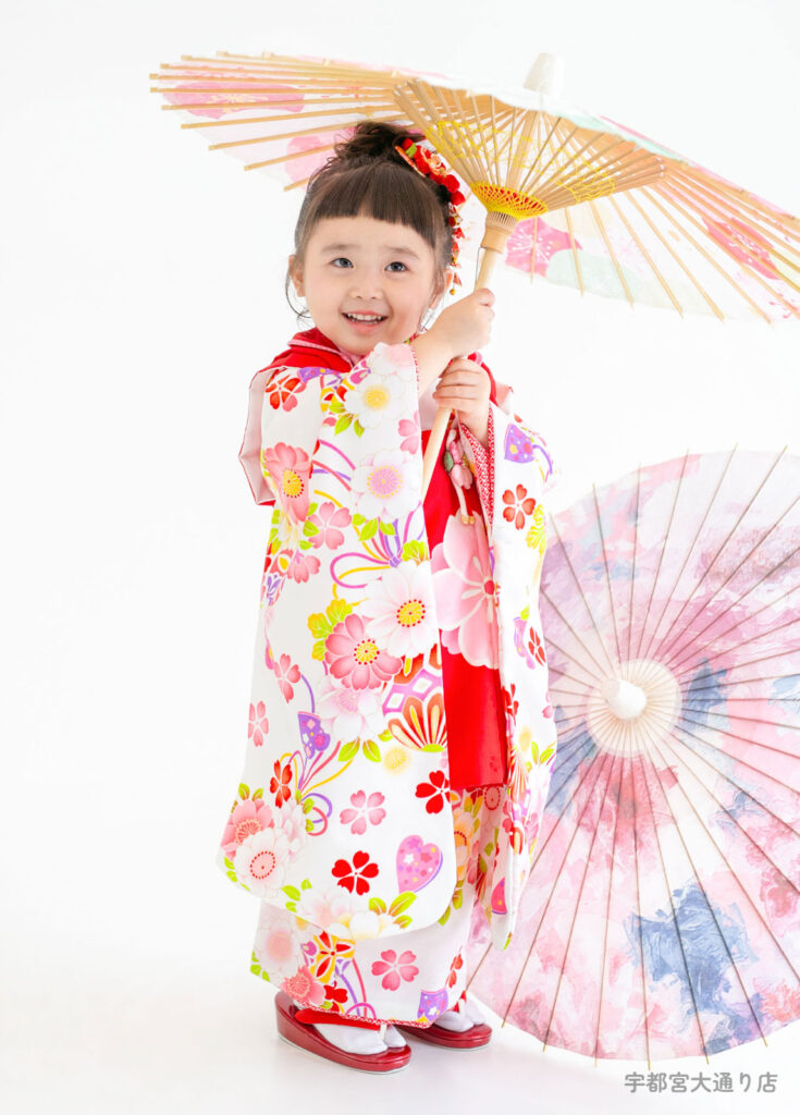 五三３歳着物：白い着物に真っ赤な被布を着た、ぱっつん前髪がかわいい３才の女の子。