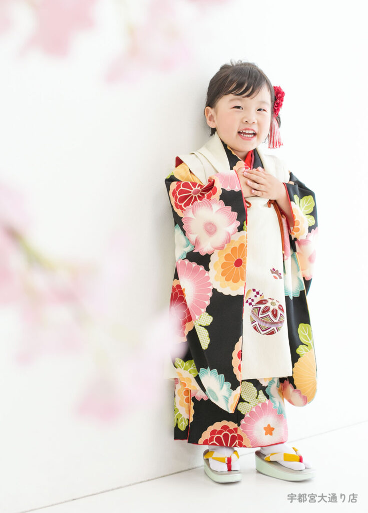 七五三３歳着物：黒い着物に和菓子のような花柄がかわいい着物を着た３才の女の子。