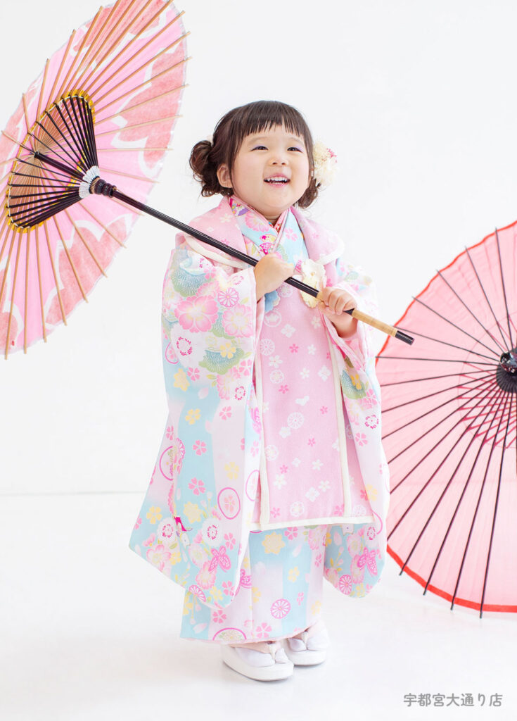 七五三３歳着物：水色にピンク、小さな女の子が大好きな色を組み合わせた着物を着て笑う３才の女の子。