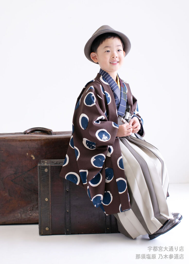 七五三５歳着物：水玉のブラウンのオシャレな着物を着てスーツケースに座る５才の男の子。