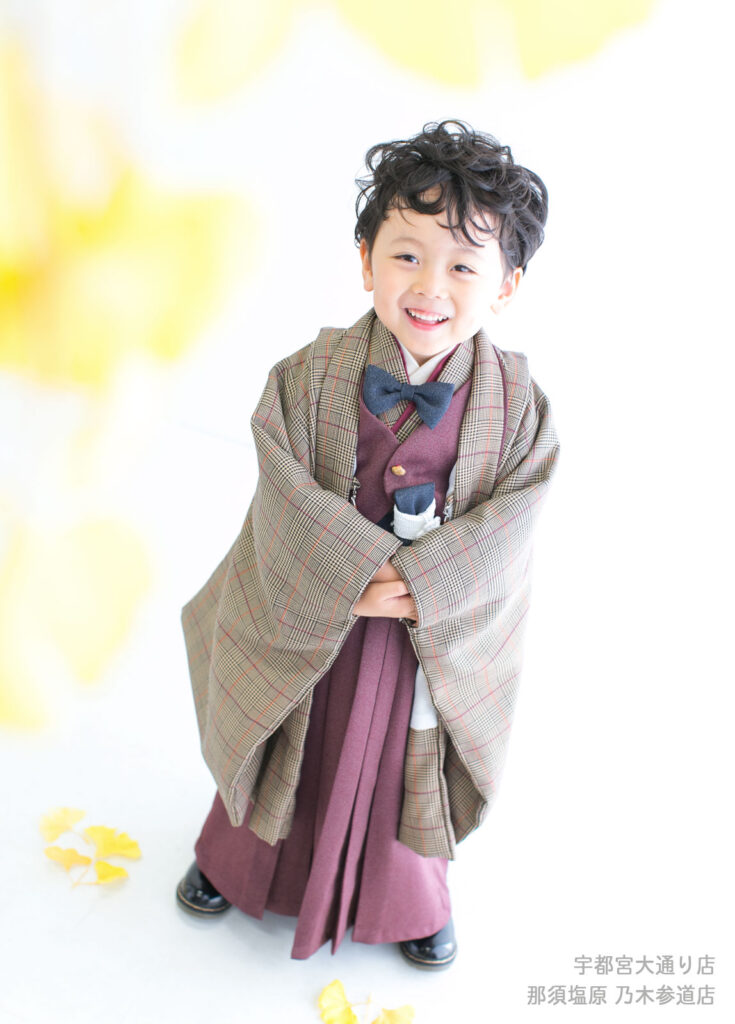 七五三５歳着物：チェック柄に蝶ネクタイが付いた着物を着たカーリーヘアの５才の男の子。