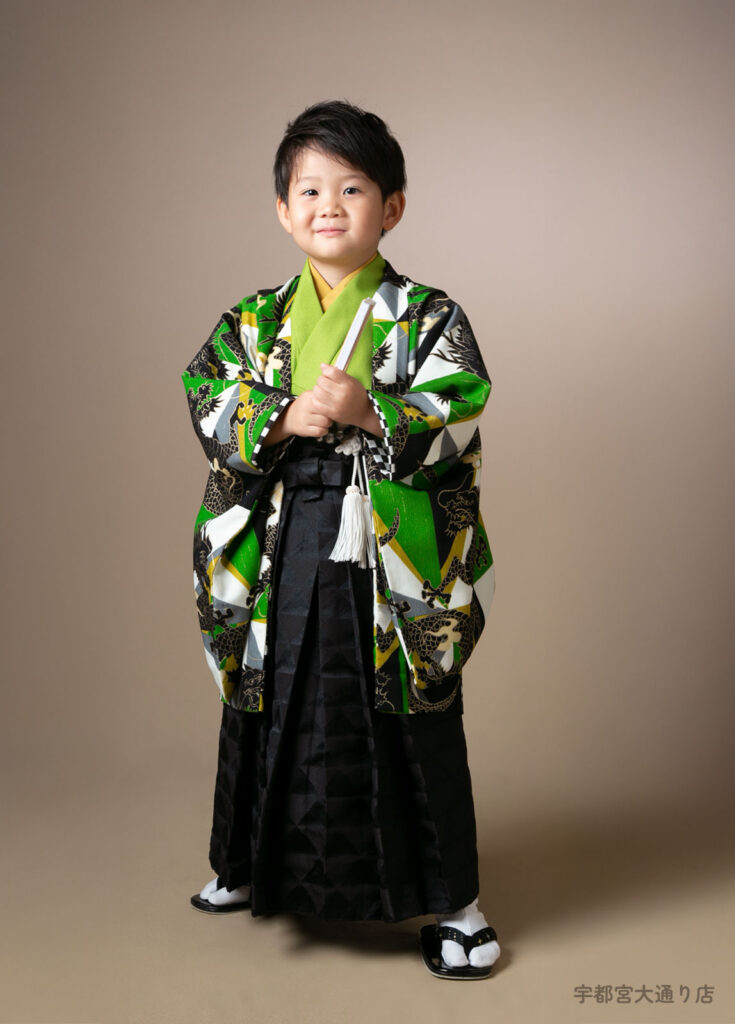 七五三５歳着物：緑の幾何学模様に黒いドラゴンが躍る着物を着た５才の男の子。