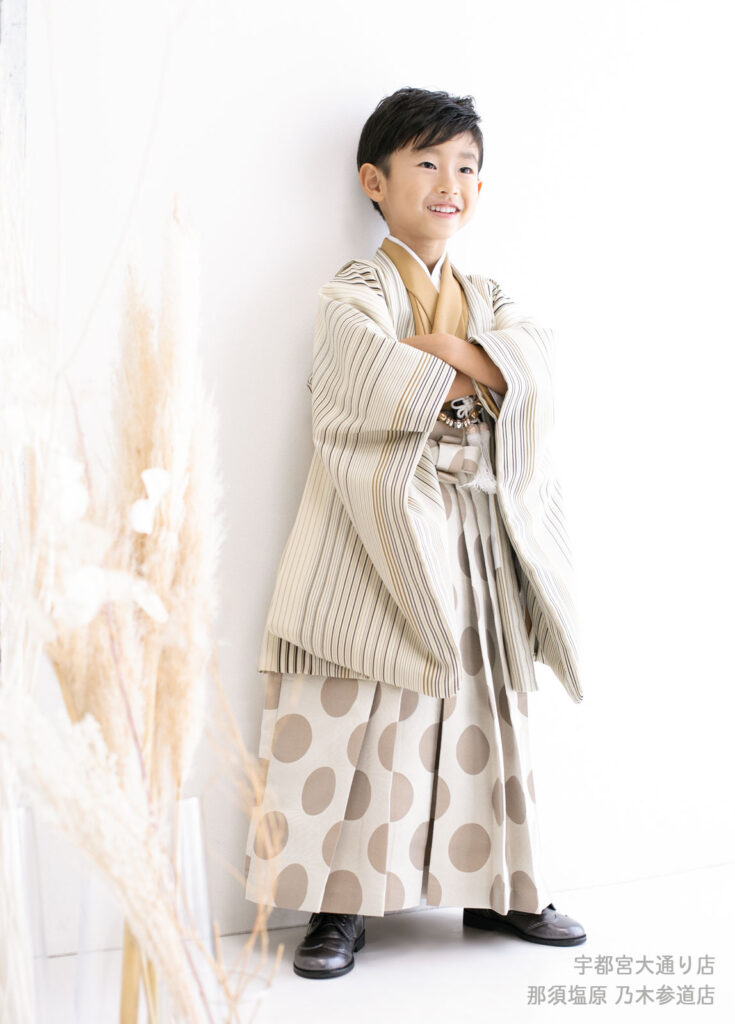 七五三５歳着物：ストライプとドット柄の淡いベージュの着物を着て腕を組む５才の男の子。