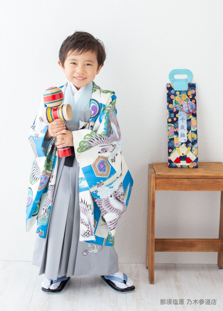 七五三５歳着物：ブルーの柄がたくさんある着物を着てけん玉をもった５才の男の子。