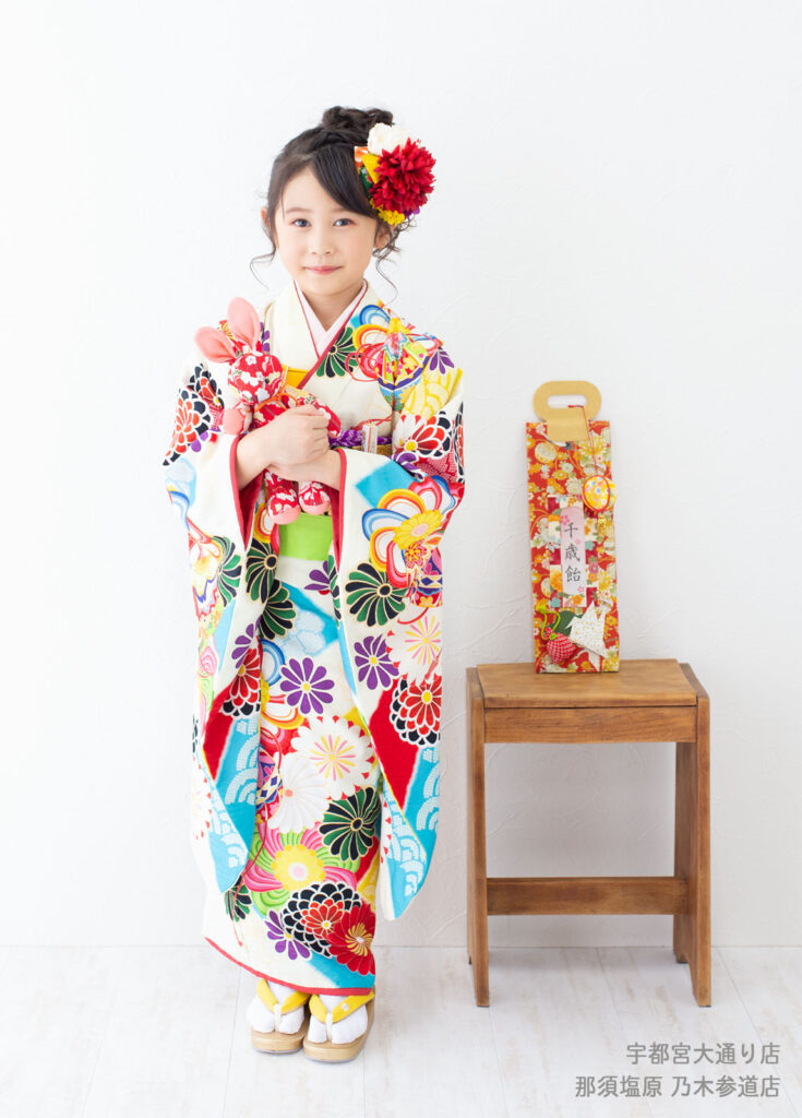 七五三７歳着物：白地にカラフルな花がたくさん描かれた着物を着た7歳の女の子。