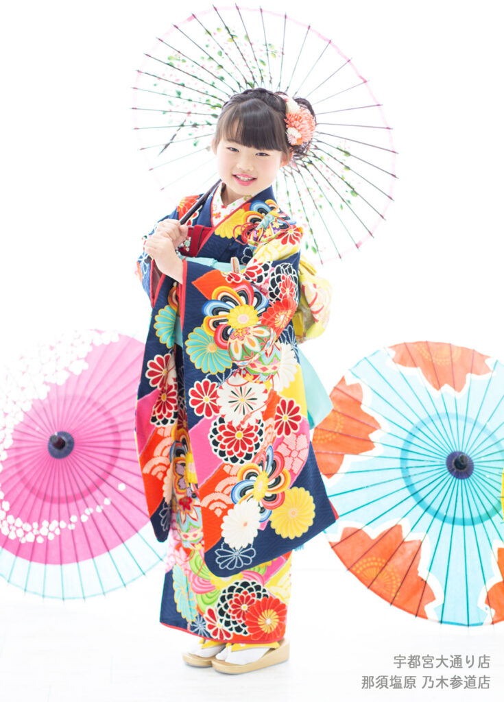 七五三７歳着物：紺色にカラフルな花模様の着物を着た7歳の女の子。