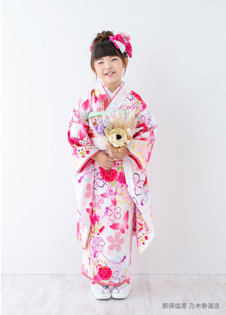 七五三７歳：華やかなピンク色の花や蝶が描かれた着物を着た７才の女の子。
