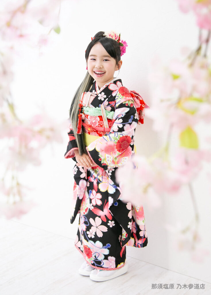 七五三７歳着物：黒地にピンクの花と蝶が描かれた着物を着た７才の女の子。