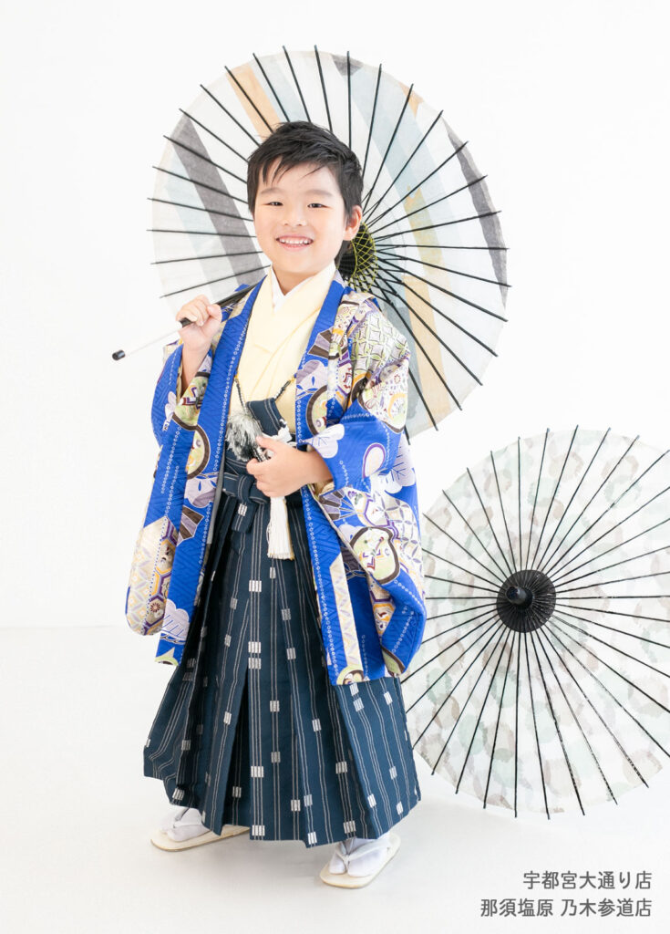 七五三５歳着物：鮮やかなブルーの着物を着て和傘をさす５才の男の子。