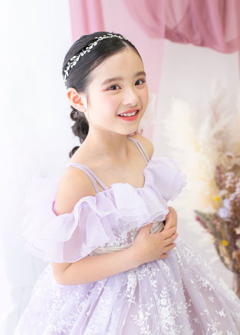七五三：チュールやレースのあしらいが豪華なオフショルダーのドレスを身にまとい。両手を胸元で合わせて笑う7歳の女の子