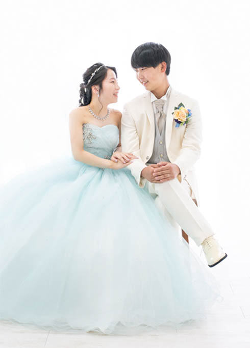 ウェディング：カラードレスを着た新婦と白いタキシードを着た新郎が見つめ合う様子